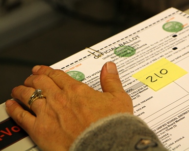 An elections office worker handles a ballot