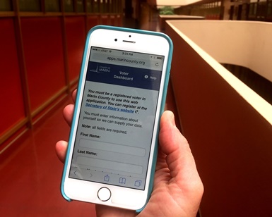 A human hand holds an iPhone with the Voter Dashboard on the screen