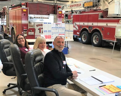 Three polling station workers sit at tables inside a Kentfield fire station on Election Day.