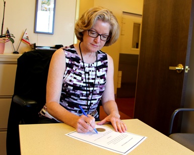 Registrar of Voters Lynda Roberts signs a document declaring the primary election complete.