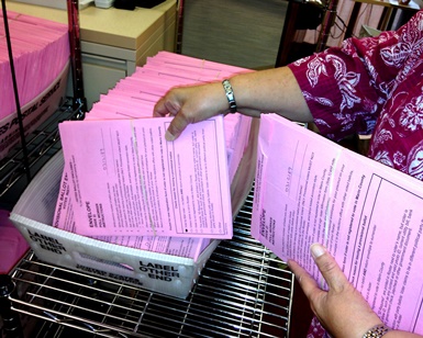 A close-up view of ballots being sorted, showing the hands of an election worker.