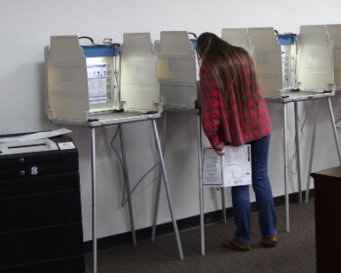 A woman fills out her ballot at a voting booth on election day.