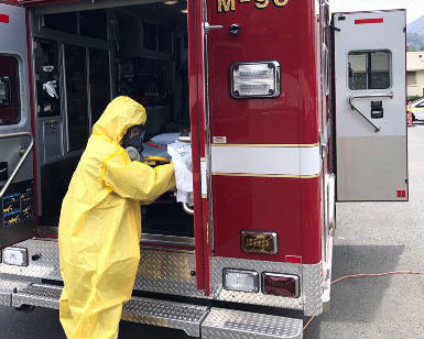 A contractor wearing a hazmat suit cleans out the inside of an ambulance.