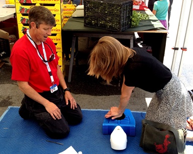 A trainer on the left trains a woman on the right how to do CPR.
