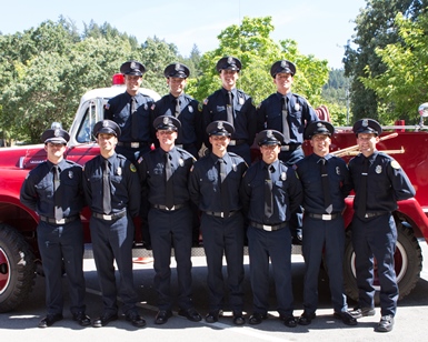Fire academy graduates pose in front of a fire truck.