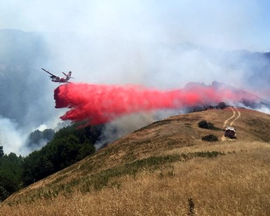 An airplane from Cal Fire lets loose on a load of fire retardant as if flies over the fire near Kent Lake.