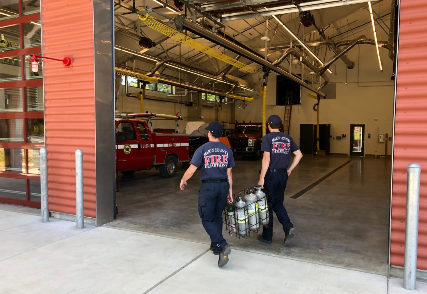 Two firefighters walk into the new Tomales Fire Station carrying heavy crates. 