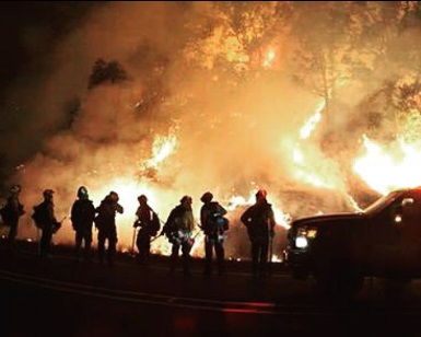 A nighttime view of Marin County firefighters silhouetted against flames at the Valley Fire in Lake County.