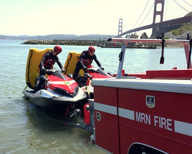 Two firefighters sit aboard personal watercraft that are used for rough-water rescues.