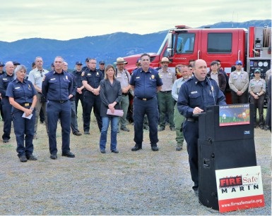 Marin County Fire Chief Jason Weber speaks at a lecturn with fire agency, parks and elected officials standing behind him.