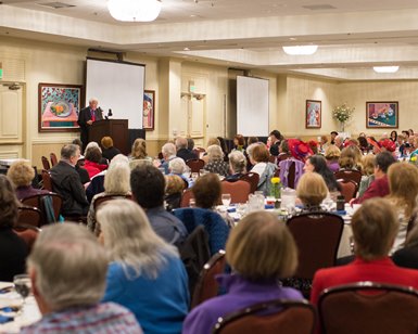 A man speaks at the lecturn in front of several hundred people at last year's symposium
