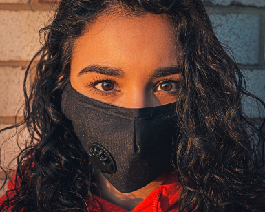 A closeup of a young woman's face as she wears a face covering to protect herself from the COVID-19 virus.