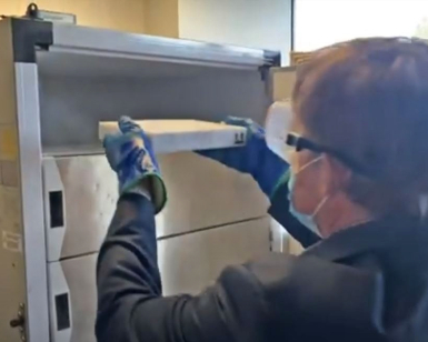 Dr. Matt Willis places a box with COVID-19 vaccine doses into a refrigerator.