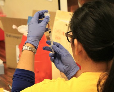 A nurse looks at needle as she prepares to give a flu shot.