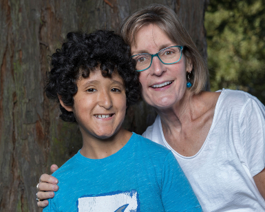 Portrait of a a female foster parent in her 50s on the right and a male foster son of about 10 years old on the left.