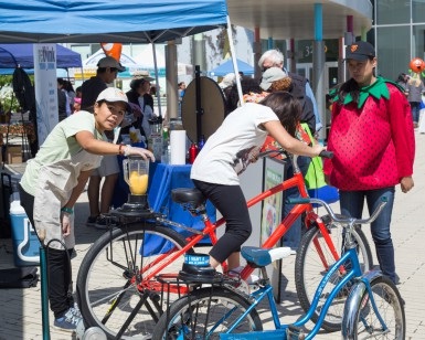 A young girl rides a stationary bike that powers a blender, which is being used to make a healthy fruit drink, at a past Fruit and Veggie Festival.