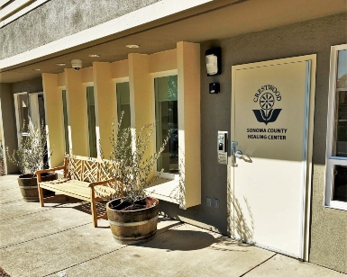 An exterior view of the Sonoma County Healing Center showing the front door, windows and a bench.