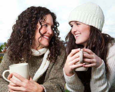 A woman in her 40s (left) chats over a cup of coffee with a girl in her teens.