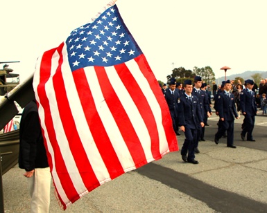 An American flag flaps as Junior ROTC cadets walk by during a Veterans Day event in 2013.
