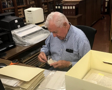 An older man thumbs through materials in a library