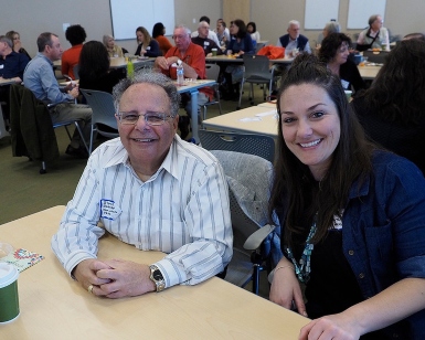 Steven Sarhad and Jennifer Zuniga sit a table and smile. Sarhad is a longtime volunteer, and Zuniga was his supervisor with the health department.