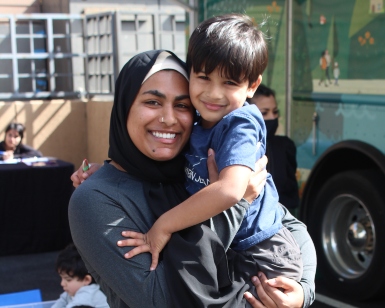 A smiling mother holds a son of about 3 years old during a library event