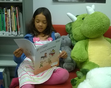 Young girl reading the new STEAM book offered to children for free this summer by the Marin County Free Library