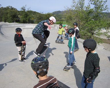 An instructor teaches young boys how to skateboard at the McGinnis skatepark