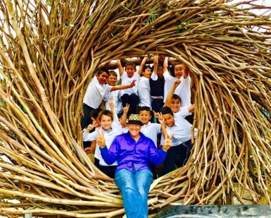 Artist Jayson Fann sits in one of his spirit nests with several children.