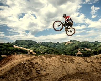 A mountain bike rider flies high over the Stafford Lake Bike Park during a jump.