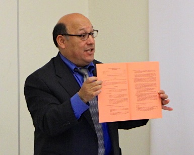 Public Defender Jose Varela holds up a sheet of paper at a public meeting.