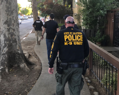 Three Probation Officers walk alongside a house as part of a compliance check on July 23, 2019.