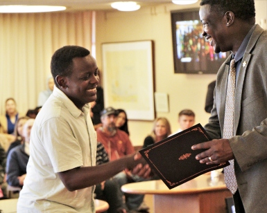 A smiling Wambua Musyoki, left, accepts a certificate from a smiling Probation Chief Marlon Washington, right.