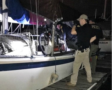 Several officers search a boat during a nighttime probation compliance check.