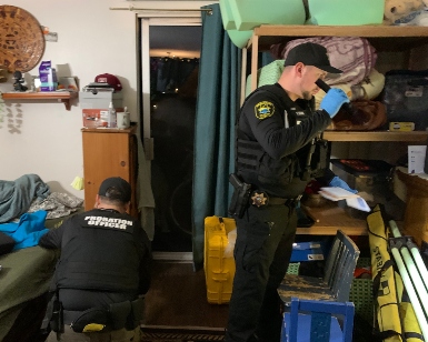 Two male Probation officers check a person's bedroom during a DUI compliance sweep.