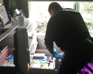 A view of a probation officer opening a draw in a DUI offender's home, looking for drugs or alcohol.