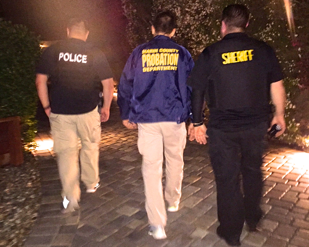 Law enforcement officers from police, probation and sheriff walk during a narcotics sweep.