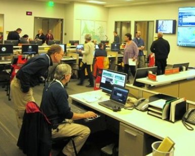 A dozen people are shown working in the Emergency Operations Center in San Rafael during a training session.