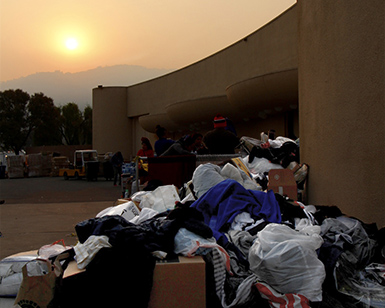 A pile of donated clothing in the foreground and the sun with a brown sky in the background.