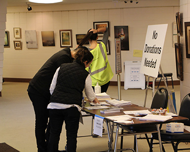 Several county employees sign in at a registration table at the wildfire evacuation shelter.