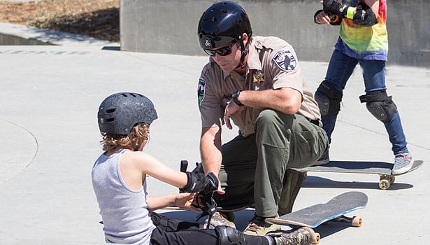 Park ranger assisting skateboarder