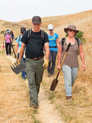 Group of volunteers holding tools heading out to project site