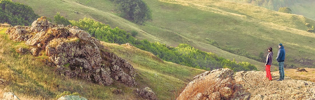 Man and woman standing on a rock looking out on the view of Loma Alta