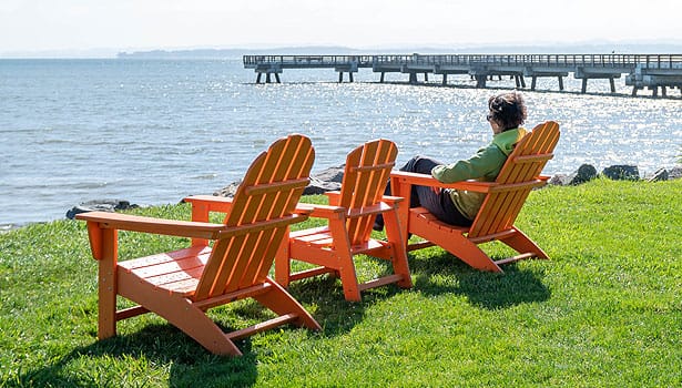 Woman sitting in orange Adirondack chair next to McNears pier