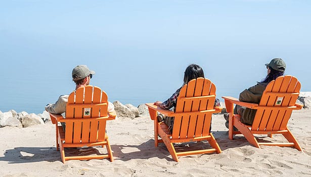 Three friends sitting on the beach in Adirondack chairs
